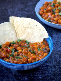 two bowls filled with beans and tortillas on top of a black countertop