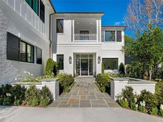 a large white house with lots of windows and bushes in front of the entrance to it