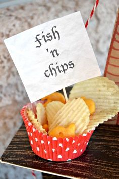 a cupcake with chips and a sign on it that says fish n chips in red paper