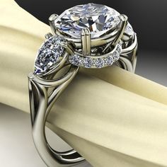 a close up view of a diamond ring on top of a white cloth with a black background