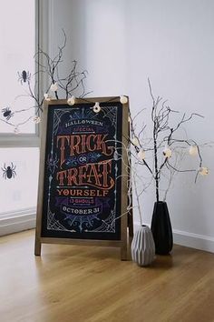 a trick or treat chalkboard next to two vases with halloween decorations on them