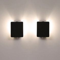 two square lights are on the wall in front of each other, one is black