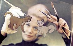 a person holding two pencils in front of an image of a cat and a mouse