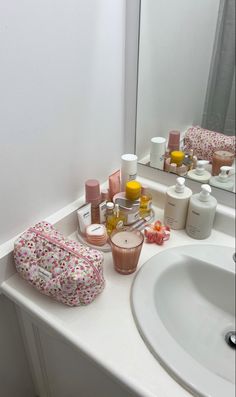 a bathroom sink with many different items on the counter and in front of it is a mirror