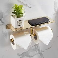 two rolls of toilet paper are hanging on the wall next to a potted plant