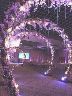 an archway decorated with purple flowers and lit candles is the focal point for this wedding reception