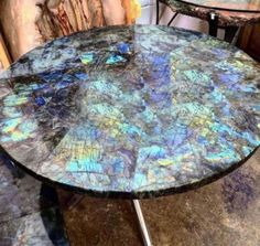 a table that has been painted with blue and purple paint on it, sitting in front of some wood logs