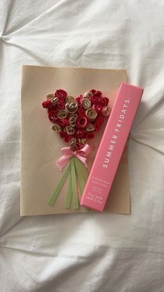 a bouquet of flowers sitting on top of a card next to a pink box with ribbon