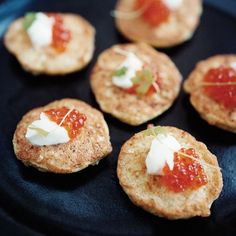 small crackers topped with cheese and sauce on a black plate