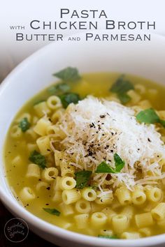 a white bowl filled with pasta and parmesan cheese on top of broth