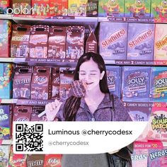 a woman standing in front of a store display filled with candy boxes and chewing gums