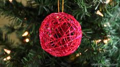 a red ball ornament hanging from a christmas tree