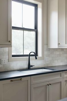 an empty kitchen with white cabinets and black counter tops is seen in this image from the window