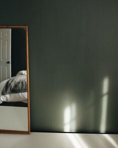 a mirror sitting on top of a white counter next to a bed in a room