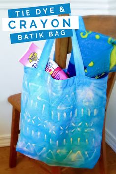 a blue bag sitting on top of a wooden chair next to a sign that says tie dye and crayon batikbag