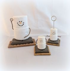 three toilet paper holders with snowman faces on them, sitting on top of coasters