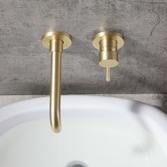 two golden faucets on the side of a white sink