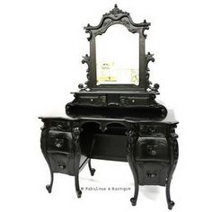 an ornate black vanity with mirror and drawers