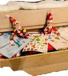 two elf figurines sitting on top of a wooden box filled with christmas cards