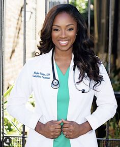 a woman wearing a white lab coat and green shirt standing in front of a gate