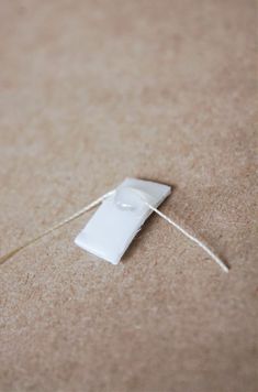 a piece of white paper tied to a string on top of a brown carpeted floor