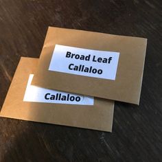 two brown envelopes sitting on top of a wooden table with labels reading broad leaf and callao