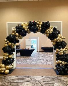 a black and gold balloon arch in the middle of a carpeted room with tables