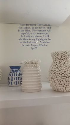 three white vases sitting on top of a shelf next to each other in front of a quote