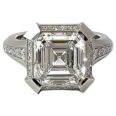 An architecturally powerful yet sleek diamond statement ring from Geoffrey Good. Featuring a single GIA-certified natural Asscher Cut Diamond of 6.01 carats, mounted in our exclusive émerge-style setting and accented by an additional .49 carats of single-cut melee diamonds. Total diamond weight for the ring is 6.50 carats. The center diamond is certified for H color, VS1 clarity; the surrounding stones are E-F color, VS+ clarity. Finger size 6.5 currently with some adjustment possible. Geoffrey Asscher Cut Diamond Ring, Oval Cut Diamond Rings, Fred Leighton, Cushion Cut Diamond Ring, Contemporary Engagement Rings, Statement Rings Diamond, Platinum Diamond Engagement Rings, Asscher Cut Diamond, Diamond Stacking Rings