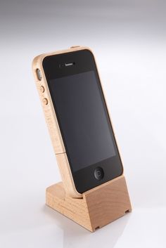 an iphone in a wooden stand on a white surface