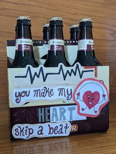 four bottles of beer sitting on top of a wooden table next to a sign that says, you make my heart skip about