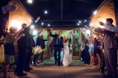 a bride and groom walk down the aisle as their guests hold sparklers in front of them