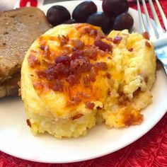 an omelet with bacon and bread on a white plate next to some grapes