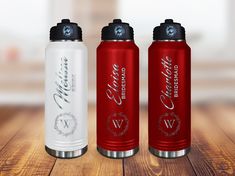 three red and white water bottles sitting on top of a wooden table