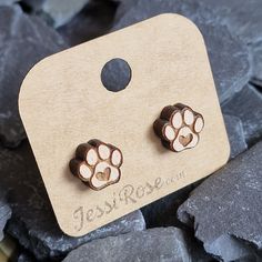 a pair of earrings with paw prints on them sitting next to some rocks and stones