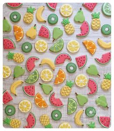 decorated cookies are arranged on a table with fruit and pineapples in the background