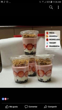 four small cups with strawberries and granola in them on top of a table