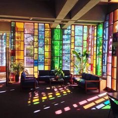 the sun shines through stained glass windows in a living room with couches and tables