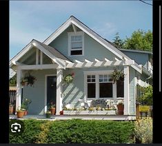 a small house with white trim and flowers on the front porch is seen in this image