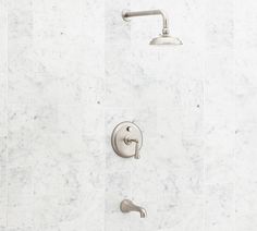 the shower head and hand shower faucet are in an all white marble bathroom