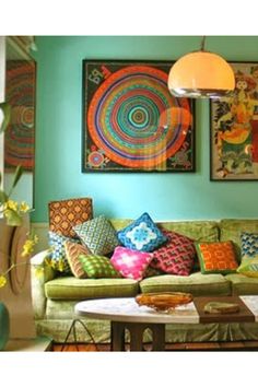 a living room filled with green couches and colorful pillows on top of each other