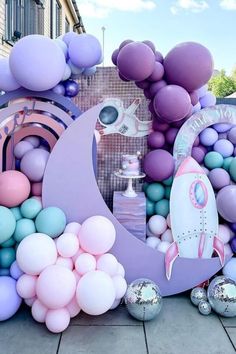 an assortment of balloons are arranged on the ground in front of a wall with a rocket ship