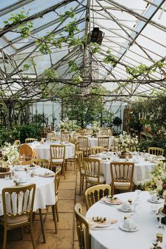 an indoor dining area with tables and chairs set up for a formal function in the greenhouse