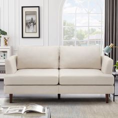 a living room with a white couch and coffee table in front of a large window