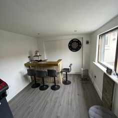 a room with chairs, a table and a dart board on the wall in it