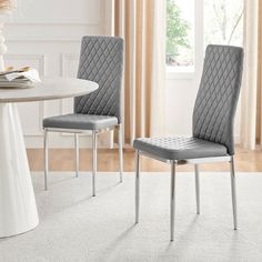 two gray chairs sitting in front of a white table