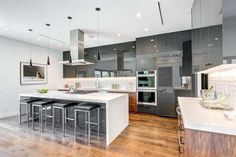 a large kitchen with stainless steel appliances and white counter tops, along with wooden flooring