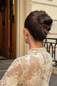 a woman with her back to the camera, wearing a white dress and gold earrings