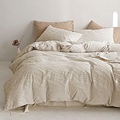 an unmade bed in a white room with pillows and blankets on top of it