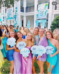 a group of women standing next to each other in front of a building holding fan shaped signs